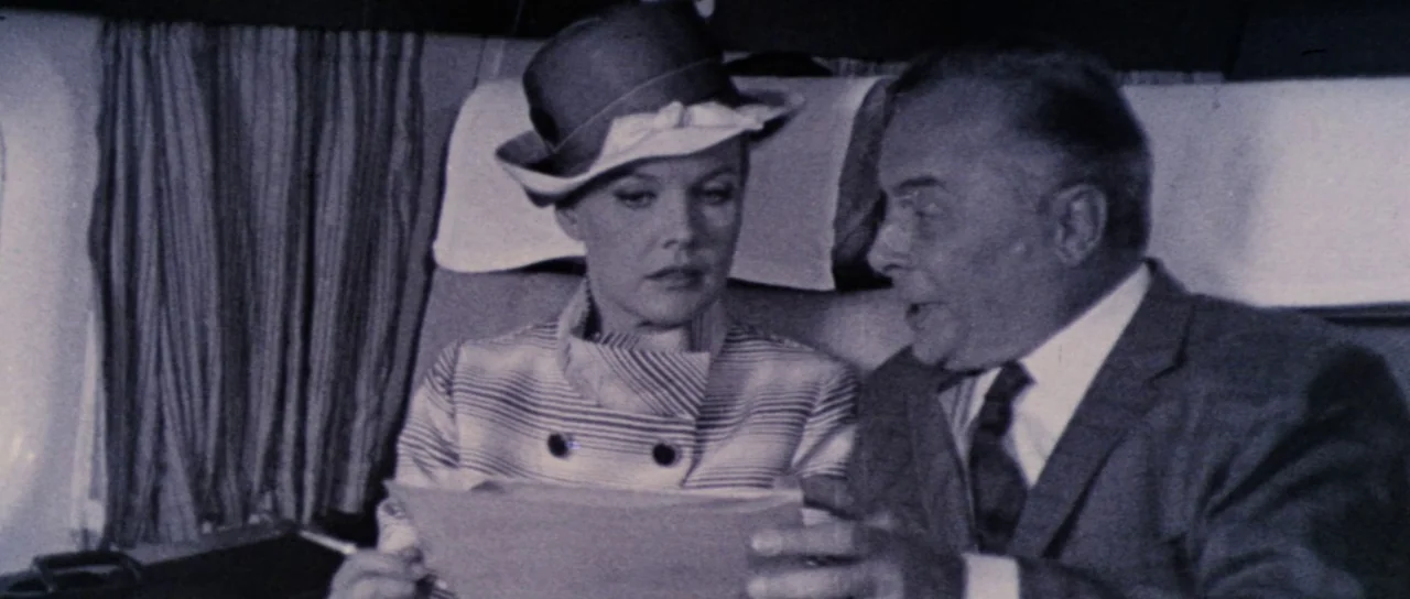Orgasmo (1969) movie still: medium — The interior of a 1960s passenger airplane with visible window curtains and seat headrests. A man in a suit…