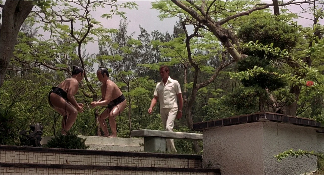 The Man With the Golden Gun (1974) movie still: fullbody — An outdoor area features stone steps and stairs leading up past two small statues. A man…