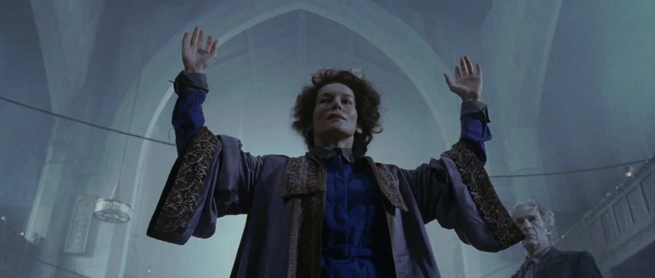 Silent Hill movie still: medium — A stone interior with high arched ceilings and soft, misty light filtering through windows. A woman in a dark robe…