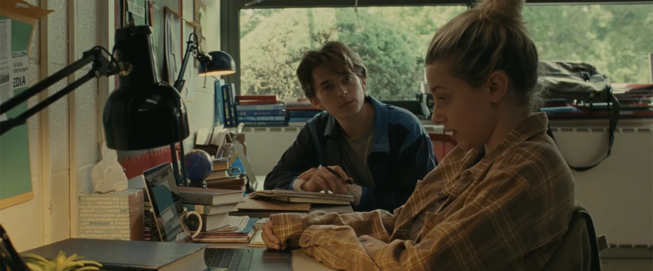 Chemical Hearts (2020) movie still: medium — A cluttered school study room with a window looking out onto leafy green trees. A young woman uses a…