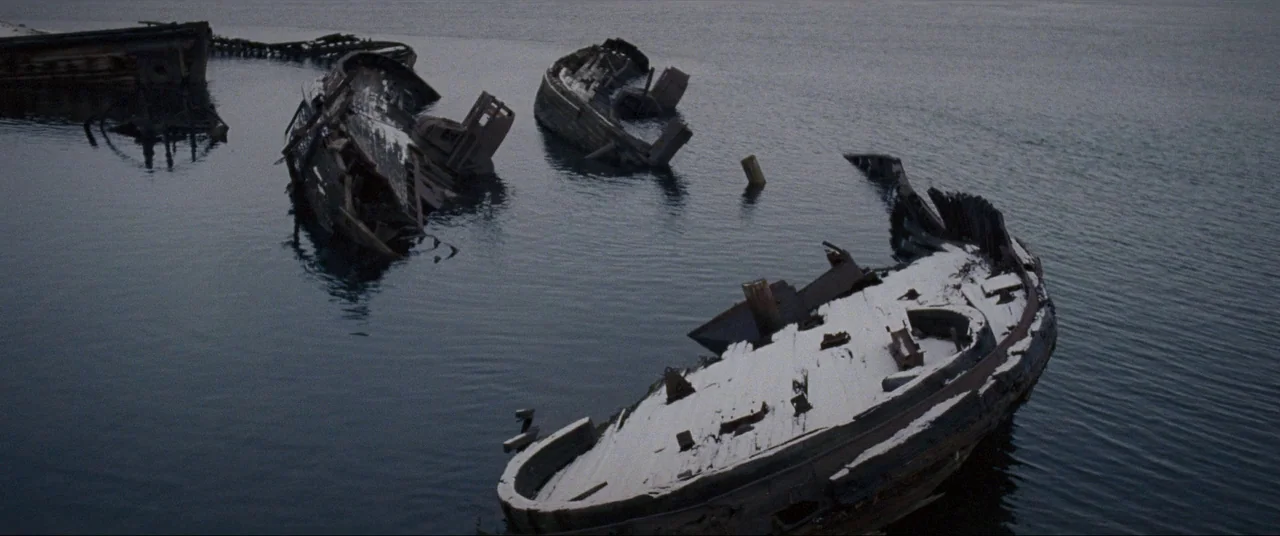 Leviathan (2014) movie still: wide — Several decaying, snow-dusted wooden ship wrecks lie partially submerged in a dark bay. The water remains…