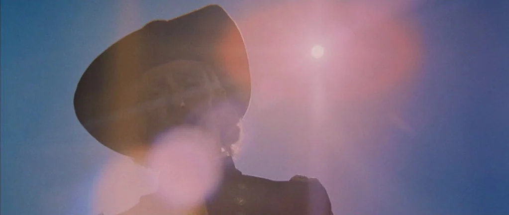 Little Big Man (1970) movie still: closeup — An open field under a bright sunlit sky serves as the backdrop. A man in military-style clothing stands…