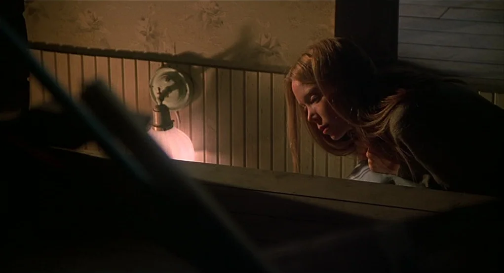 Carrie (1976) movie still: medium — A dimly lit room features textured floral wallpaper above wooden beadboard wainscoting. A young woman with long…