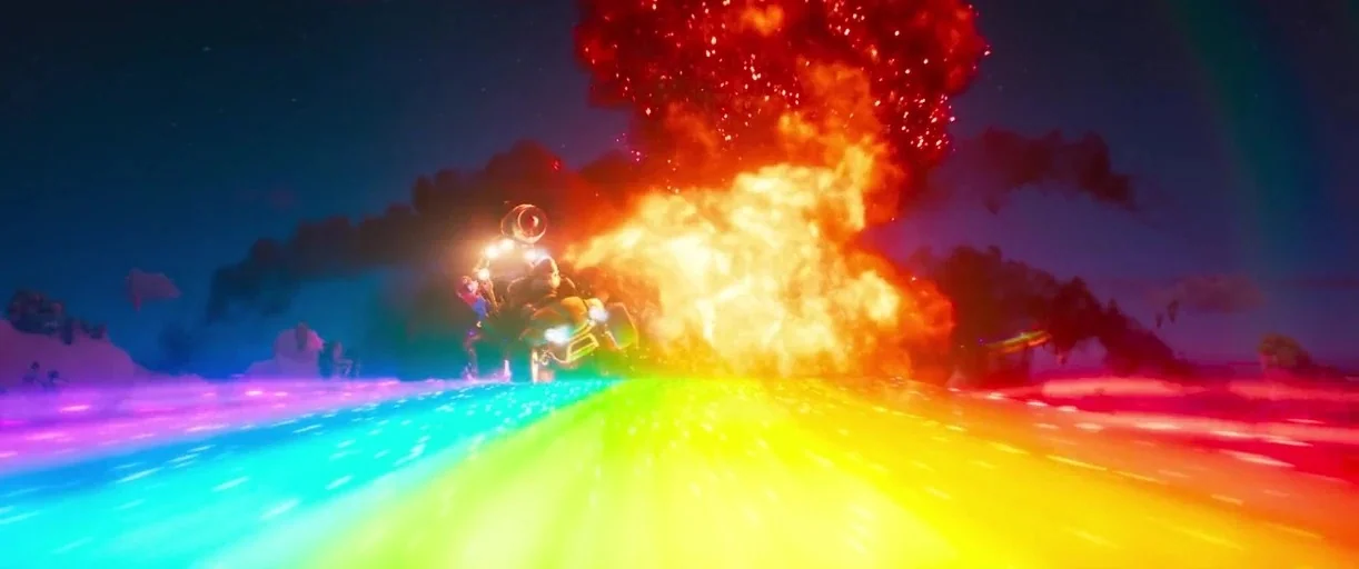 The Super Mario Bros. Movie (2023) movie still: wide — A cartoonish kart drives forward on a glowing rainbow road at night. A large fire explosion…