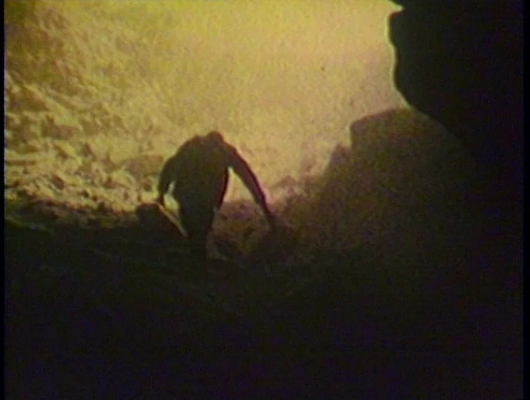 The Angelic Conversation (1985) movie still: wide — A dark, uneven cavern entrance frames the bright, overexposed exterior landscape beyond. A lone…