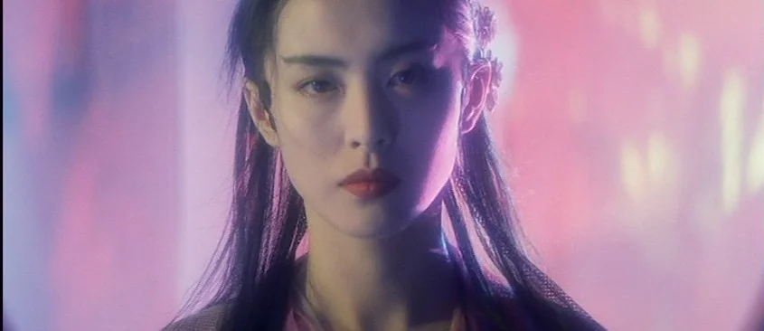 Green Snake (1993) movie still: closeup — A close-up shot focuses on a young woman against a diffused, neon-lit background. The subject maintains…
