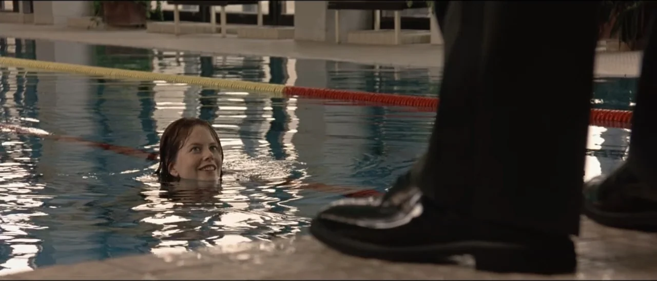 The Peacemaker (1997) movie still: medium — An indoor swimming pool with a tiled deck and lane markers in the water. A submerged woman looks upward…