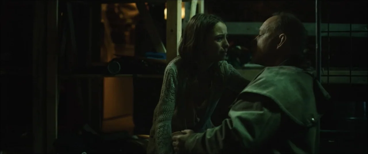 I'll Take Your Dead (2018) movie still: medium — A dim, cluttered storage space features exposed wooden beams and low-level shelving units. A young…