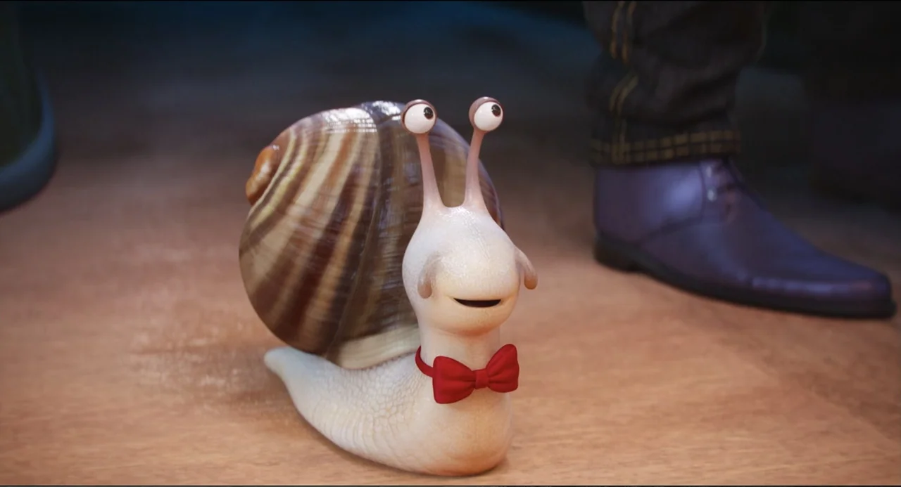 Sing (2016) movie still: medium — A light-colored wooden floor supports a small, stylized cartoon snail wearing a red bowtie. A person wearing dark…
