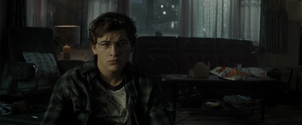 Ready Player One (2018) movie still: medium — A dimly lit room with cluttered surfaces including a coffee table with snack packaging. A young male…