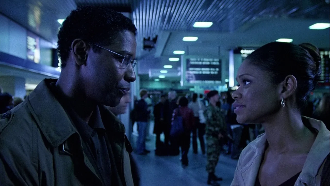The Manchurian Candidate (2004) movie still: medium — A crowded airport terminal features rows of fluorescent lights across a low ceiling. Two…