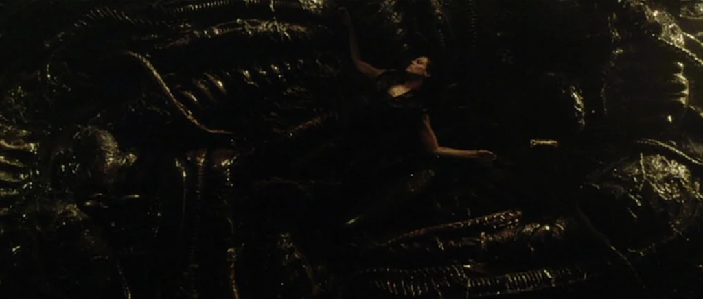Alien: Resurrection (1997) movie still: wide — A dark environment covered in wet, organic, biomechanical structures and ribbed textures. A person…