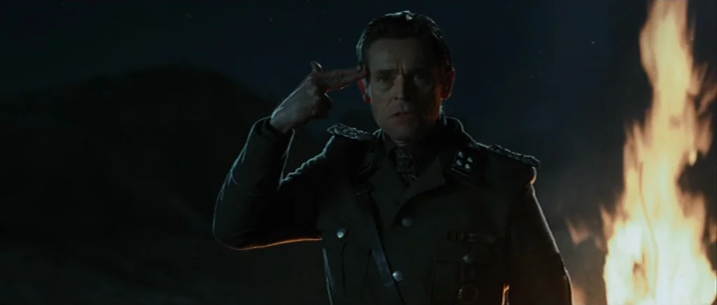 Adam Resurrected (2008) movie still: medium — An officer stands in a dark, rural exterior field at night. A fire burns to his side, casting…