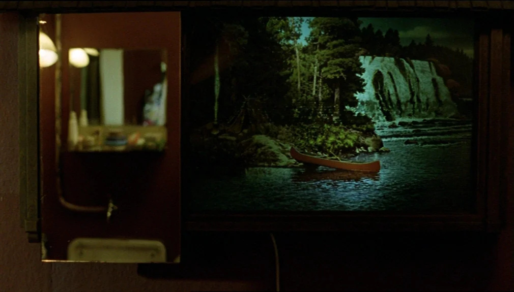 The American Friend (1977) movie still: closeup — A dimly lit room interior features a small rectangular mirror beside an illuminated scenic…