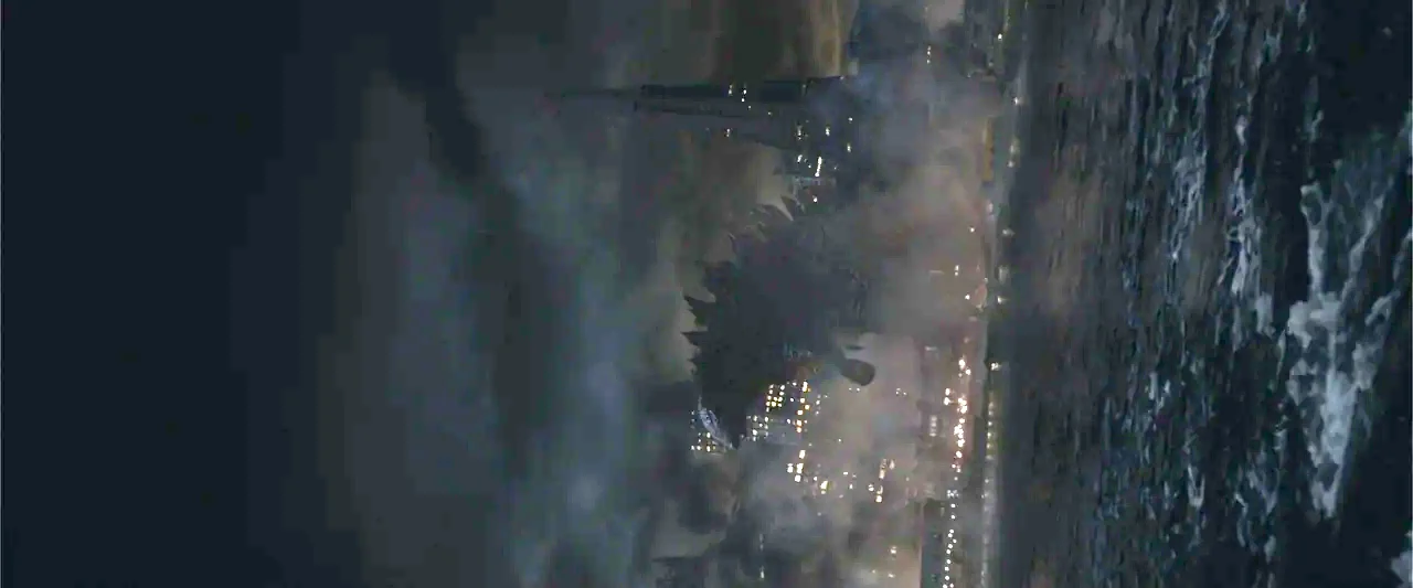 Godzilla (2014) movie still: wide — A gargantuan monster navigates dark ocean waters before a sprawling illuminated city skyline at night. The…