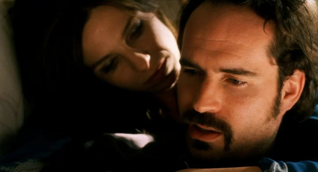 Narc (2002) movie still: closeup — A dark, out-of-focus background frames two people positioned close together. A woman rests her head behind a…