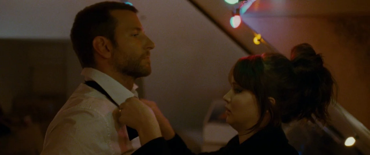 Silver Linings Playbook (2012) movie still: medium — An interior space features angled walls illuminated by decorative string lights in the…