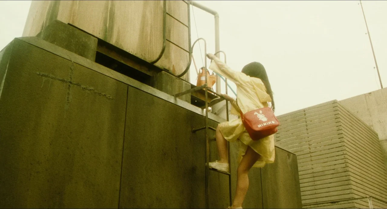 Dark Water (2002) movie still: fullbody — A tall industrial metal water tank sits on a flat concrete surface.