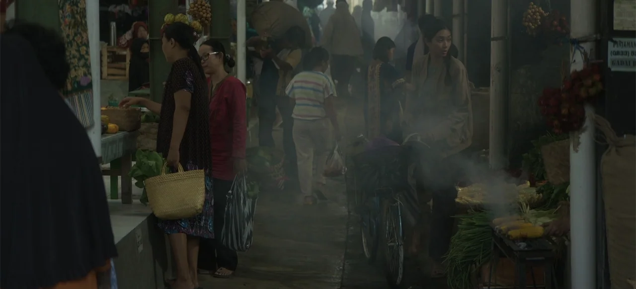 A Thousand Days (2023) movie still: medium — A crowded outdoor market aisle features multiple people shopping among various stalls and goods. A…