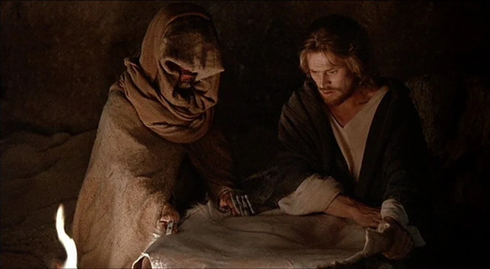 The Last Temptation Of Christ (1988) movie still: medium — A dark, uneven interior space with stone-like surfaces suggests a primitive, isolated…