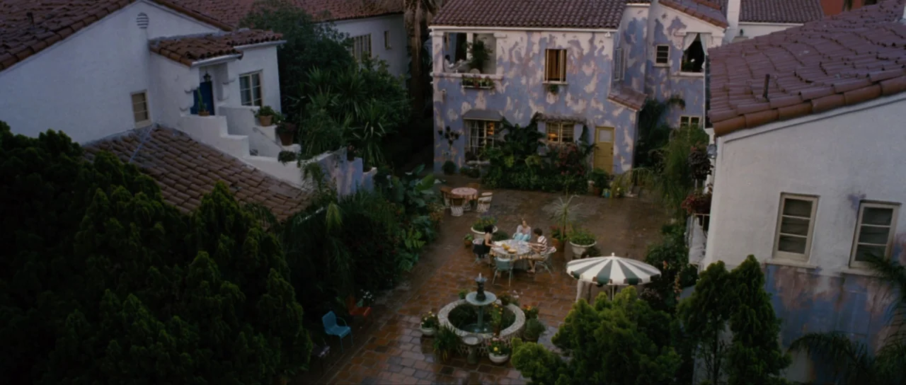 Monster-in-Law (2005) movie still: wide — A residential courtyard features tiled flooring, a central stone fountain, and surrounding stucco…