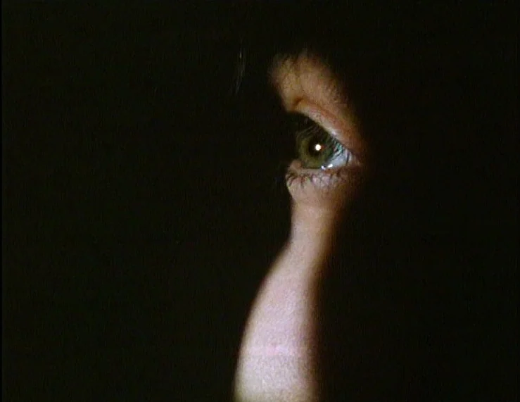 The Tempest (1979) movie still: closeup — The frame shows a tightly cropped view of a human eye in total darkness. The eye is illuminated by a…