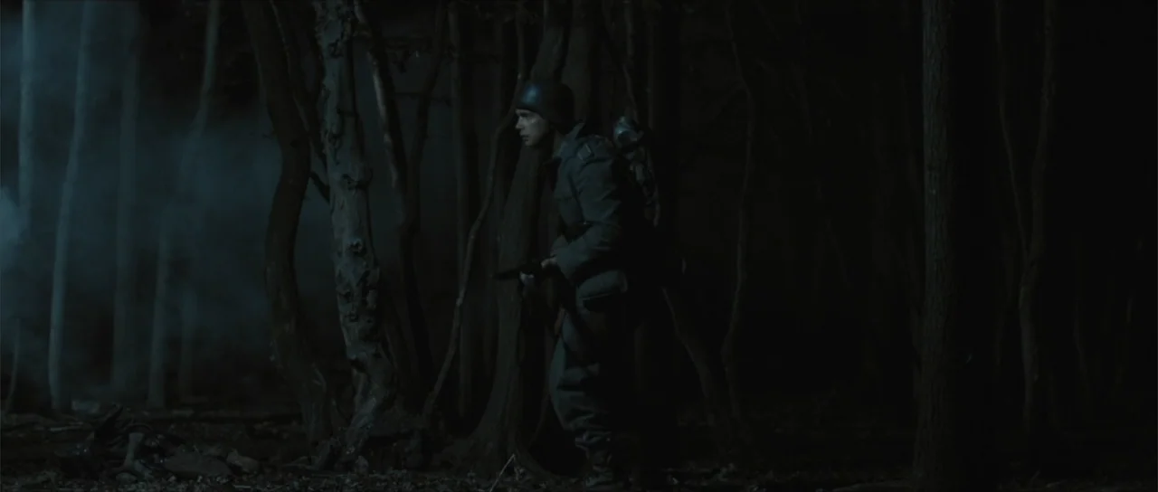 Sin retorno (2009) movie still: medium — A dark, dense forest with tall trees and thin patches of fog at night. A soldier in World War I style…