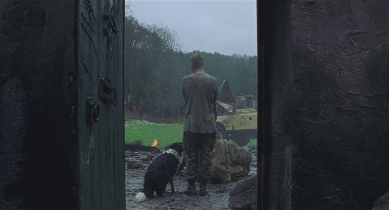 Dog Soldiers (2002) movie still: fullbody — A man and his dog stand in the doorway of a stone building ruin. Beyond the door, a damaged…