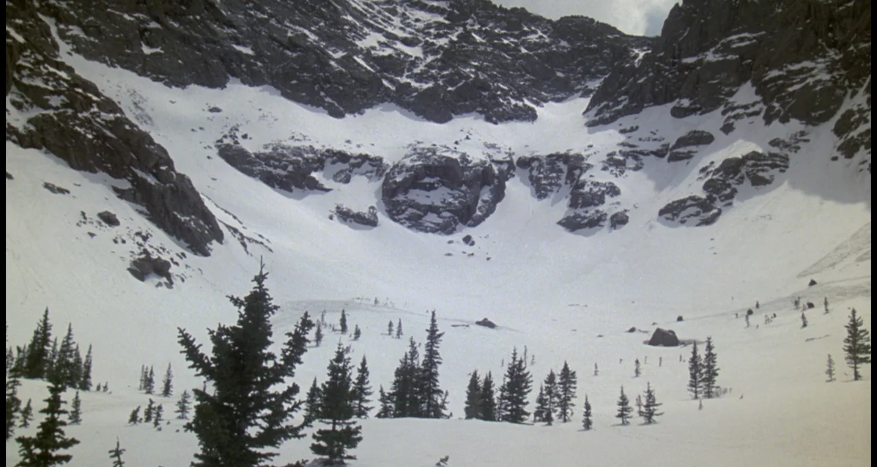 The White Buffalo (1977) movie still: wide — A vast, high-altitude alpine bowl sits surrounded by steep, snow-dusted granite peaks. Scattered…