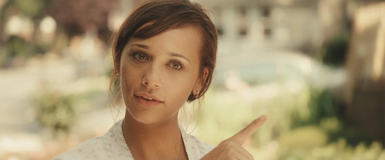 Cop Out (2010) movie still: closeup — A sunny residential street with blurred trees and houses in the background. A woman in a floral shirt points…