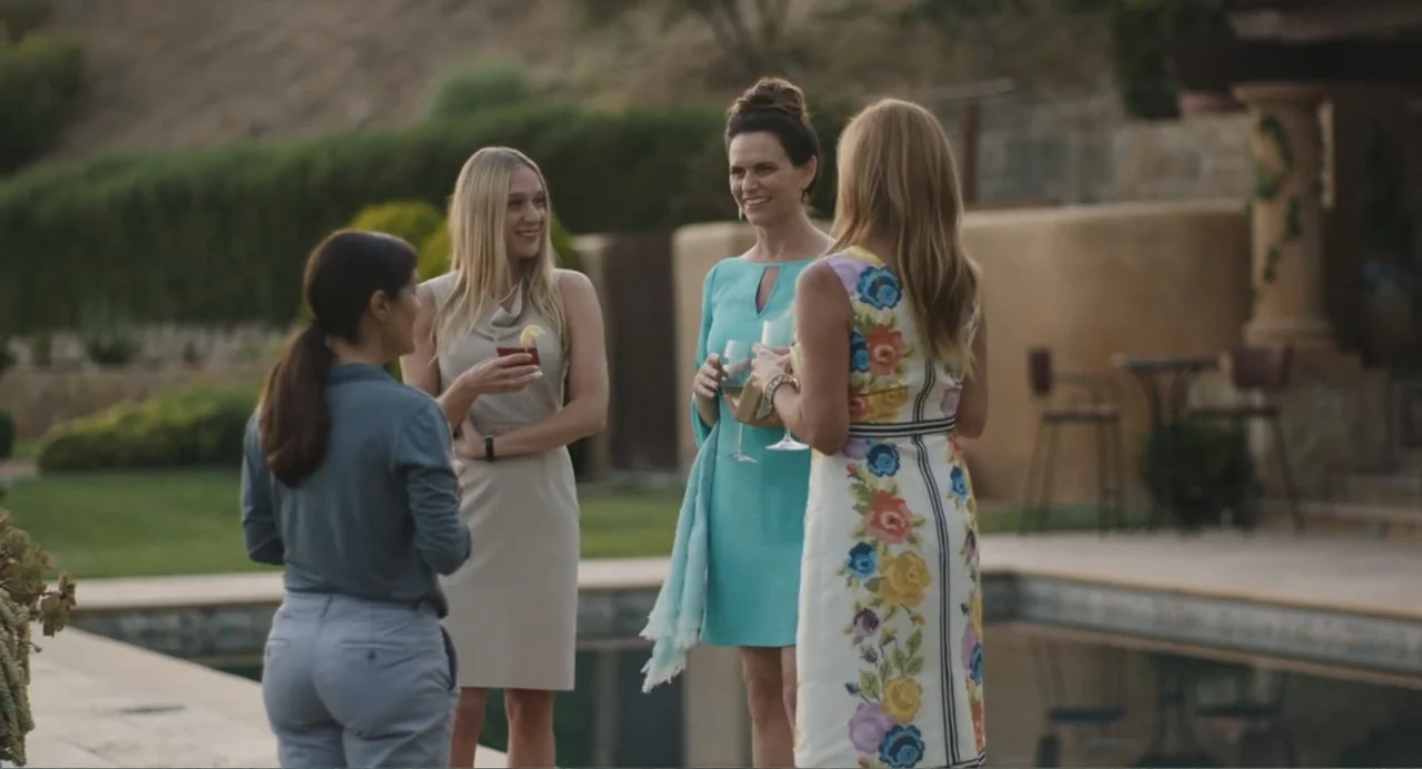 Beatriz at Dinner (2017) movie still: fullbody — Four women in summer attire gather near the edge of a swimming pool. They converse with glasses in…