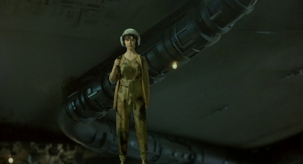 Godzilla vs. King Ghidorah (1991) movie still: fullbody — A dark, expansive industrial interior features a large mechanical pipe suspended in the…