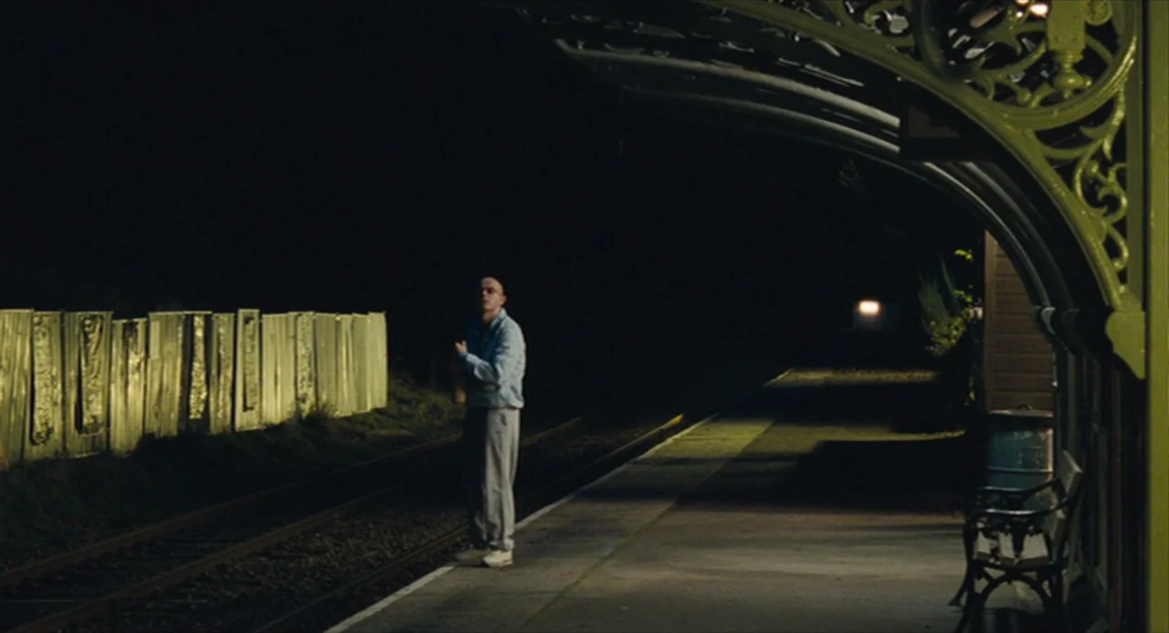 The Angel’s Share (2012) movie still: wide — A quiet train platform at night with an ornate metal roof structure overhead. A single man stands near…