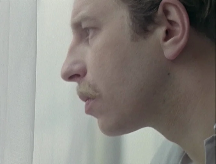 Camera Buff (1979) movie still: closeup — A close-up shot of a man's profile against a white fabric curtain. The subject gazes past the camera while…