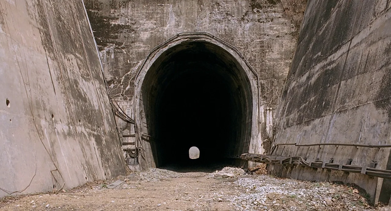 I Saw The Devil (2010) movie still: establishing — A wide concrete tunnel entrance with weathered walls sits between two angled concrete…