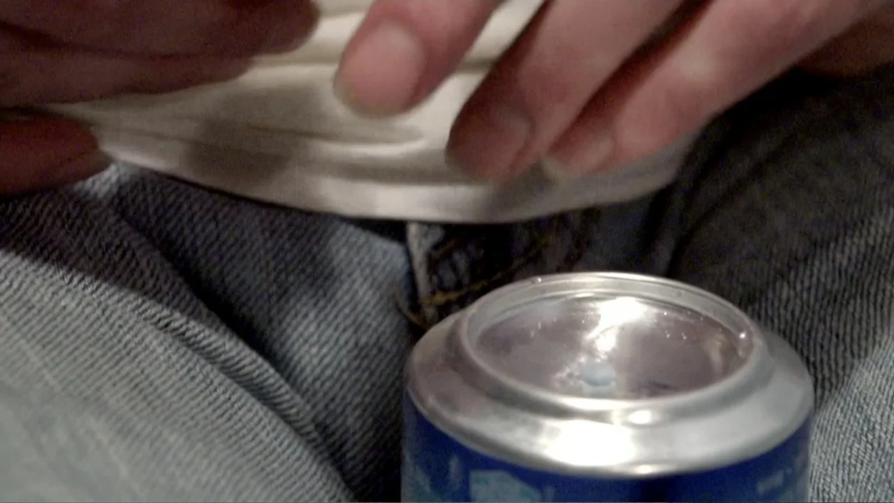 Meth Storm (2017) movie still: closeup — A close view shows a pair of hands resting on blue jeans. A metallic drink can sits prominently on the lap.