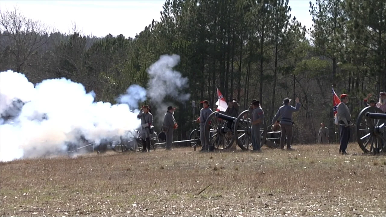 Kill Cavalry (2021) movie still: wide — A dry, open field with sparse grass and pine trees in the background. Men dressed in 19th-century military…