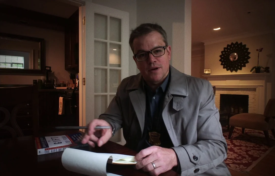 Unsane (2018) movie still: medium — A dimly lit dining room features a fireplace and dark wood furniture in background. A middle-aged man in a…