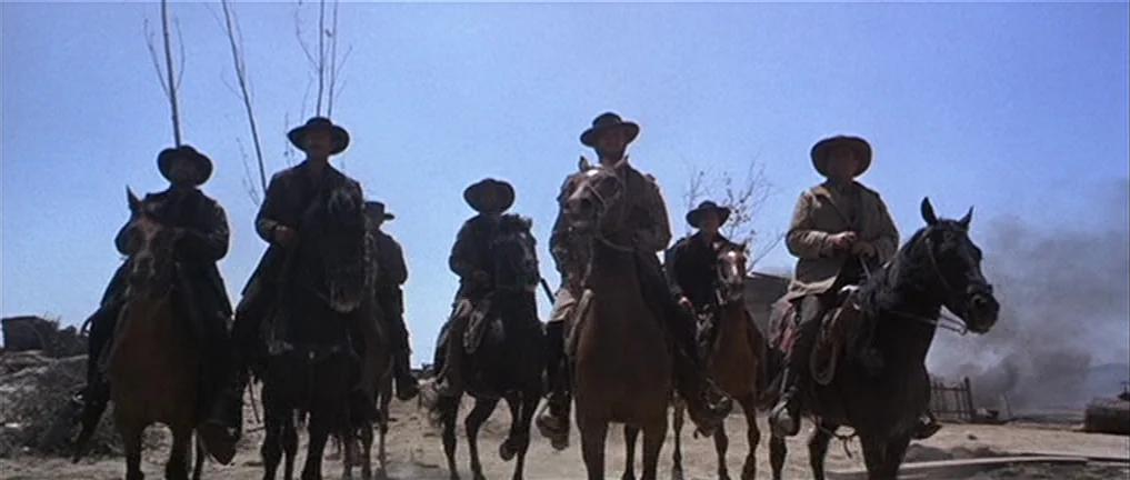 The Good, The Bad And The Ugly (1966) movie still: wide — A group of six men ride horses across a dry, dusty, open terrain. They wear western-style…