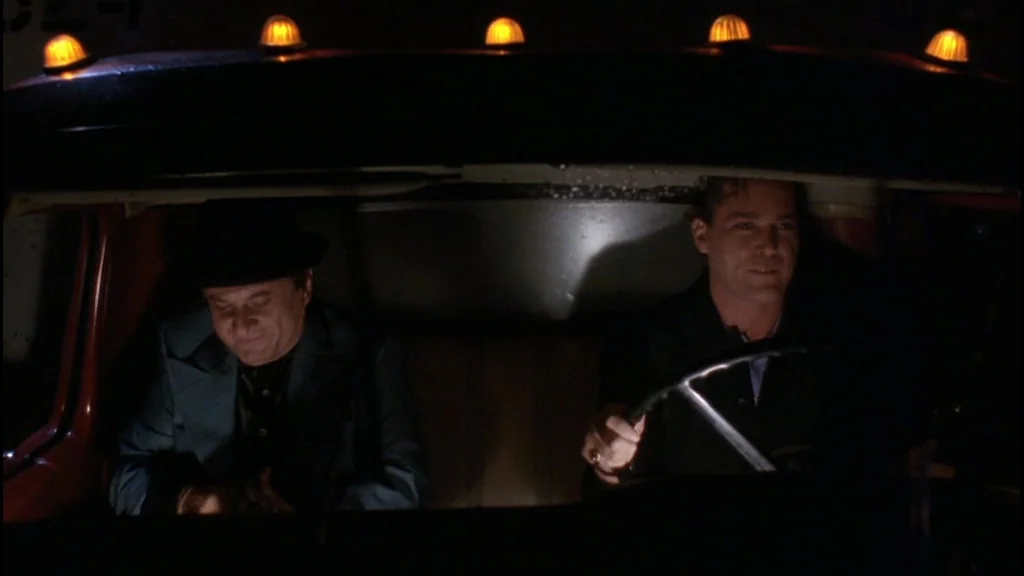 Goodfellas (1990) movie still: medium — The interior of a truck cab at night features two men sitting side by side. The driver operates the vehicle…
