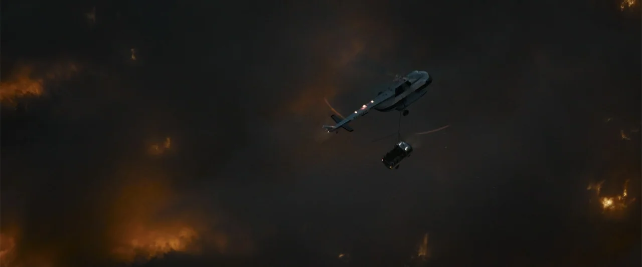 In the Line of Duty: Smoke Jumpers (1996) movie still: wide — A heavy transport helicopter carries a container suspended on a cable in the sky.…