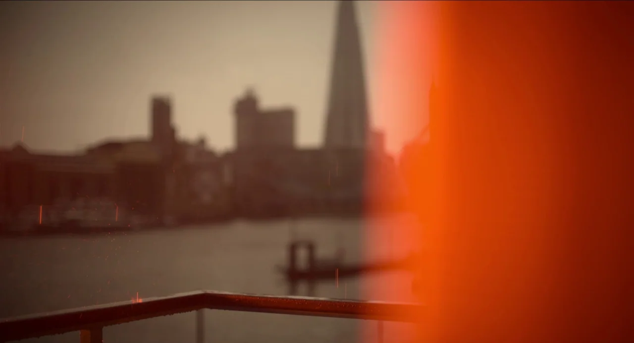 Men (2022) movie still: establishing — A view of the London skyline across the Thames is visible from a balcony. The Shard stands tall in the center…