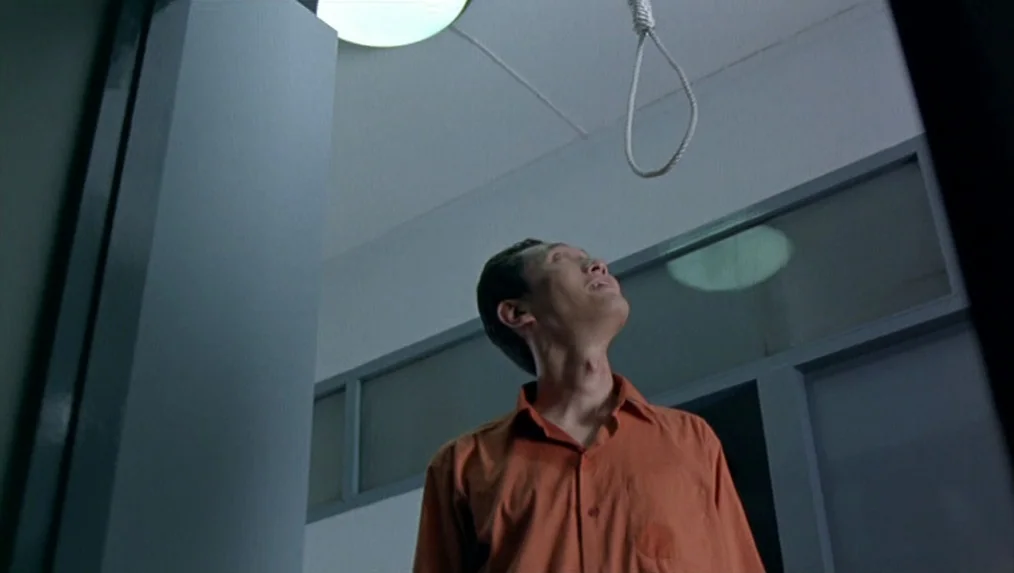 Last Life in the Universe (2003) movie still: medium — A spartan hospital room features grey partition walls and a high ceiling. An Asian man in an…