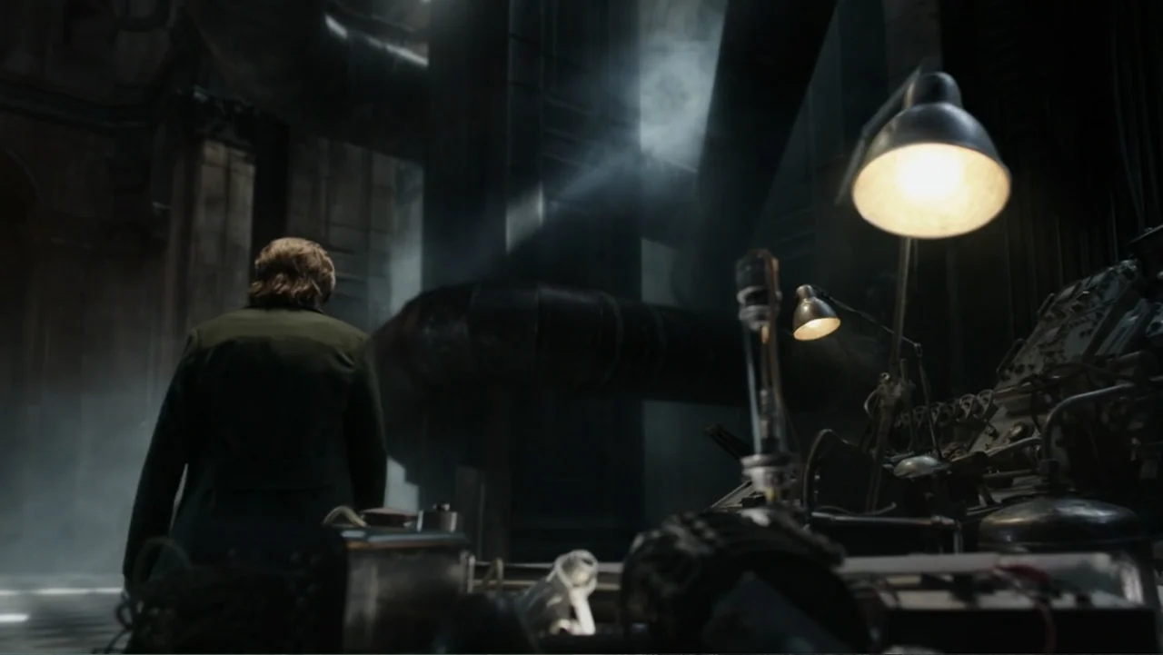 Mortal Engines (2018) movie still: medium — An industrial laboratory features exposed piping, heavy machinery, and multiple metallic work surfaces.…