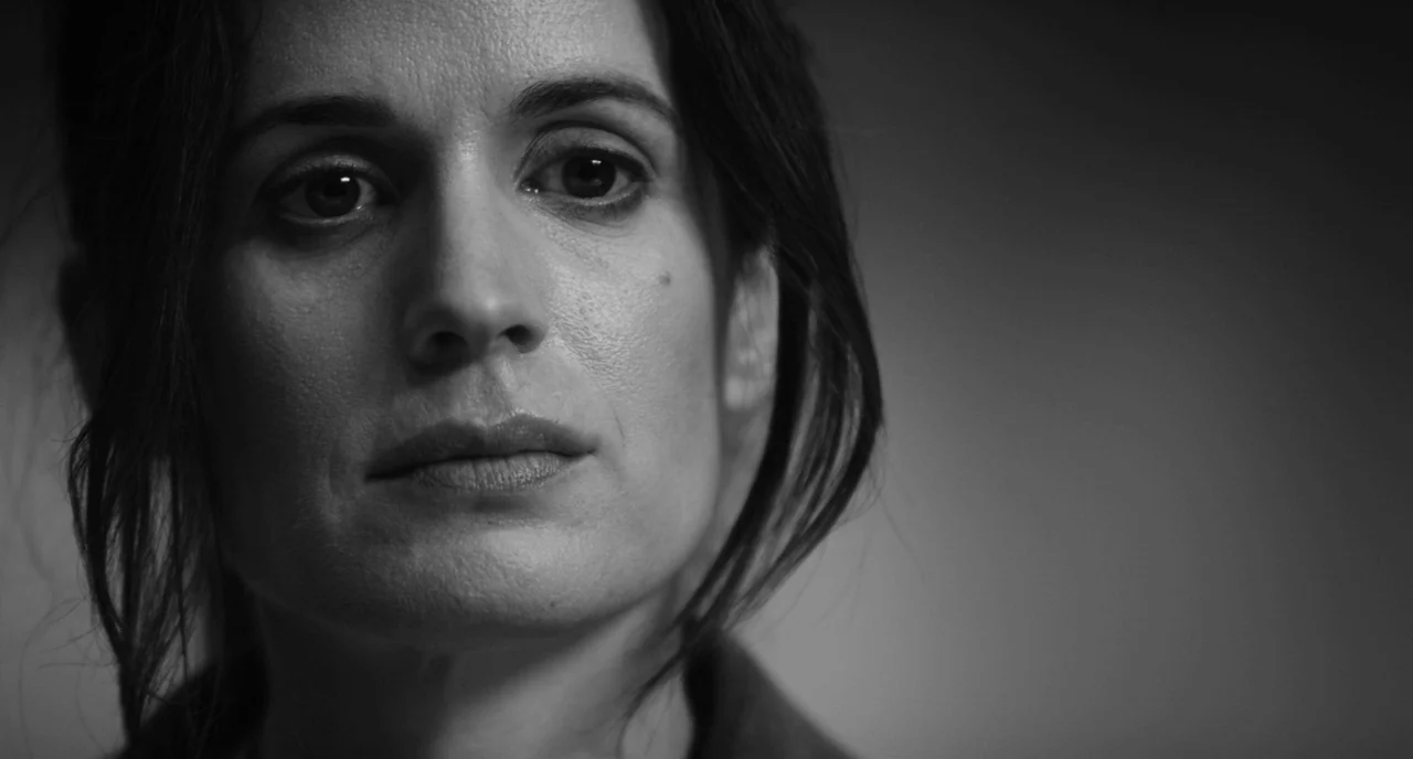 Nightmare Cinema movie still: closeup — A neutral grey studio background with soft lighting illuminating a woman's face. The subject stares ahead…
