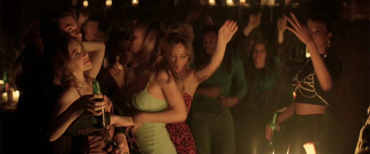 Marked Men: Rule + Shaw (2025) movie still: medium — A crowded dimly lit room filled with people socializing during an evening event. Several young…