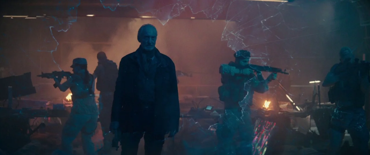 Godzilla: King of the Monsters (2019) movie still: medium — An interior space filled with smoke and debris viewed through a shattered glass panel.…