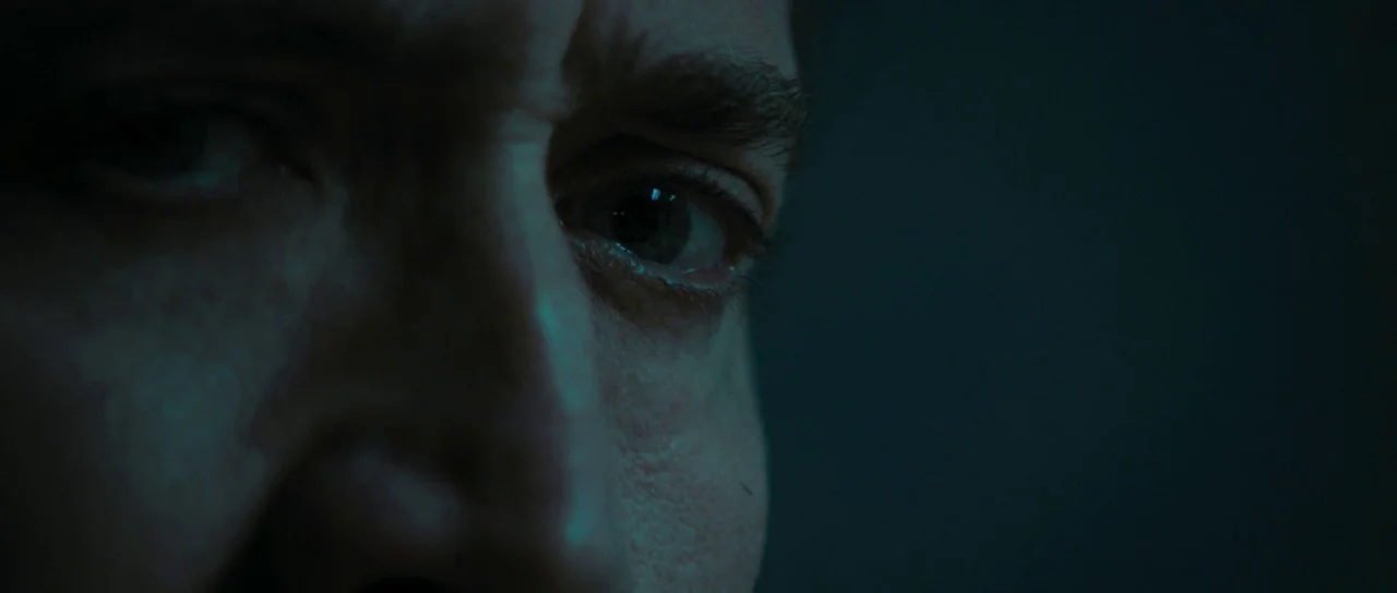 Joe (2013) movie still: closeup — A close crop focuses on a man's eye and temple in near darkness. He stares intently forward while most of his face…
