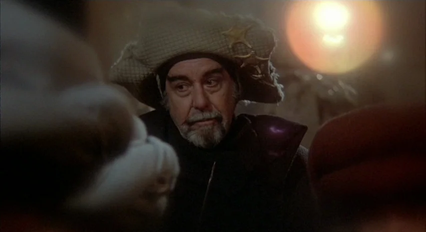 Quintet (1979) movie still: closeup — A dimly lit, indistinct space with a soft light source in the background. A bearded man wearing a brimmed hat…