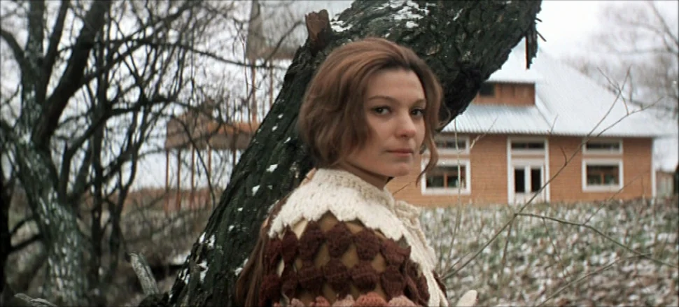 Solaris (1972) movie still: medium — An outdoor area with bare trees and a light dusting of snow on the ground. A young woman stands in front of a…